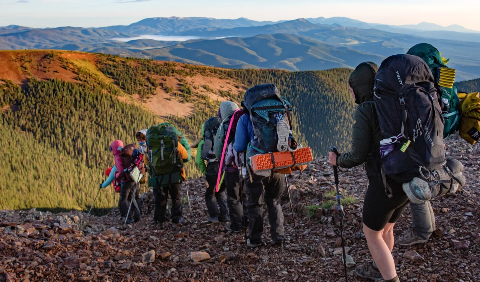Group of Scouts backpacking along a mountain ridge at sunrise