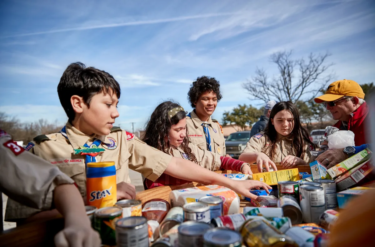 Scouts BSA youth sorting canned food donations at a community service event